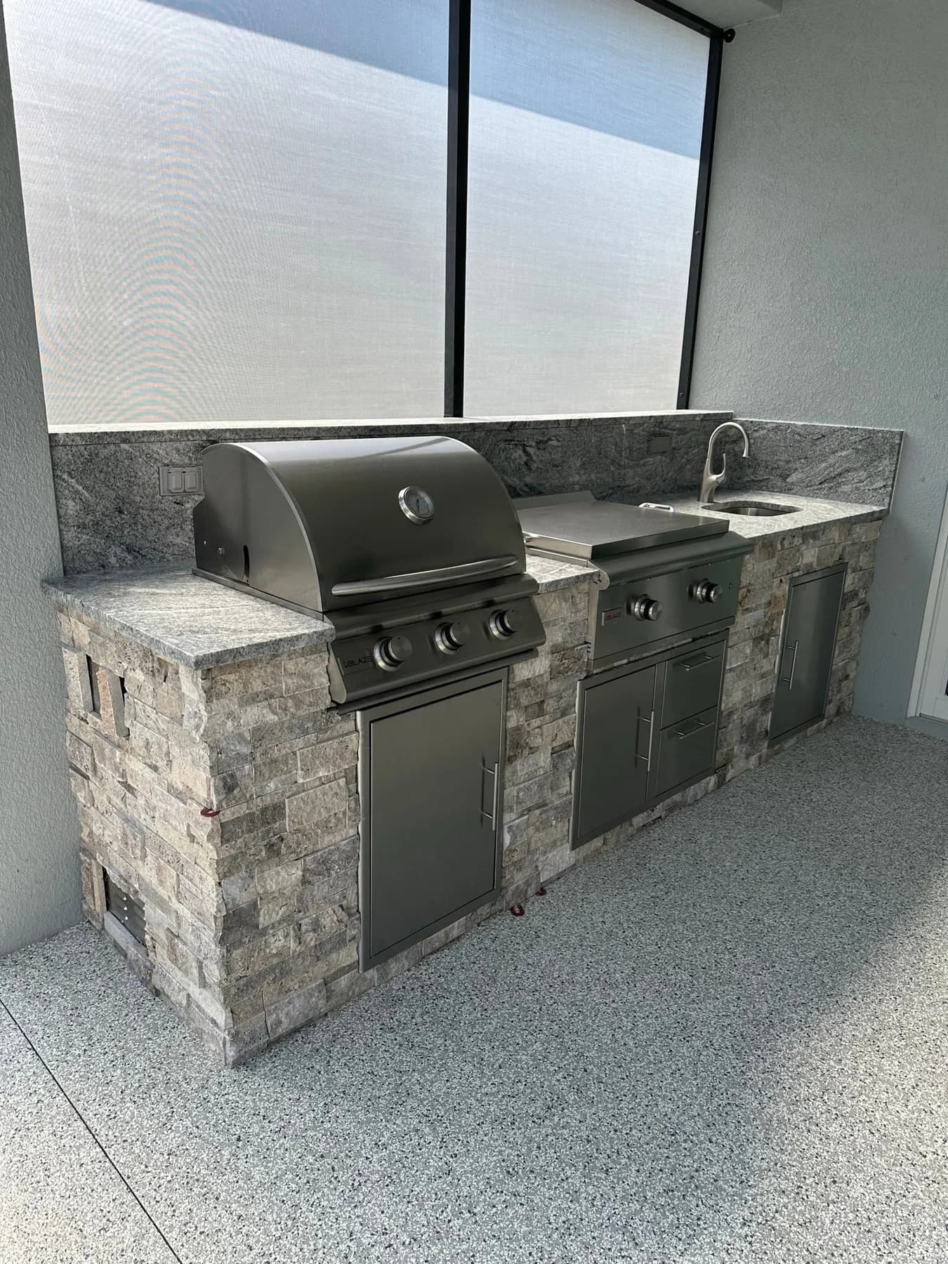 Apex built-in kitchen with stone facing, stainless appliances and a patterned countertop