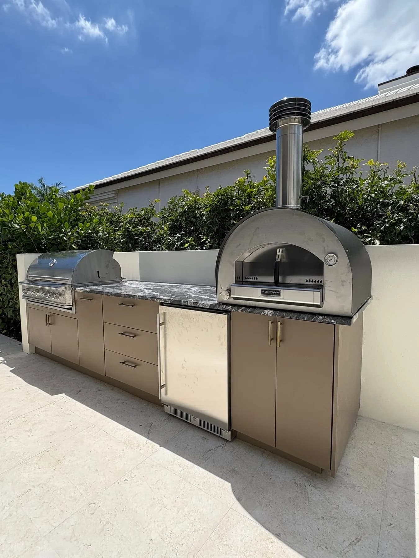 Finished outdoor cooking area with cabinetry, grill, refrigerator, and pizza oven